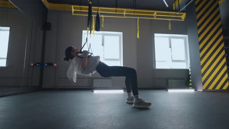 Sporty-woman-doing-TRX-exercises-in-the-gym.-Women-training-with-fitness-straps-in-the-gym.-Beautiful-lady-exercising-her-muscles-sling-or-suspension-straps.
