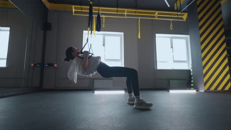 sporty woman doing trx exercises in the gym. women training with fitness straps in the gym. beautiful lady exercising her muscles sling or suspension straps.