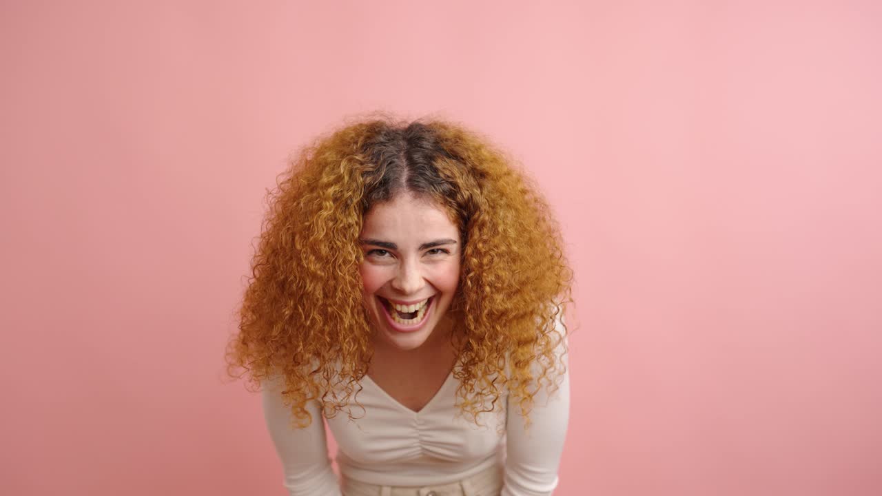 Expressive woman showing joyful emotions in pink studio