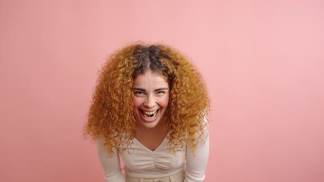expressive woman showing joyful emotions in pink studio