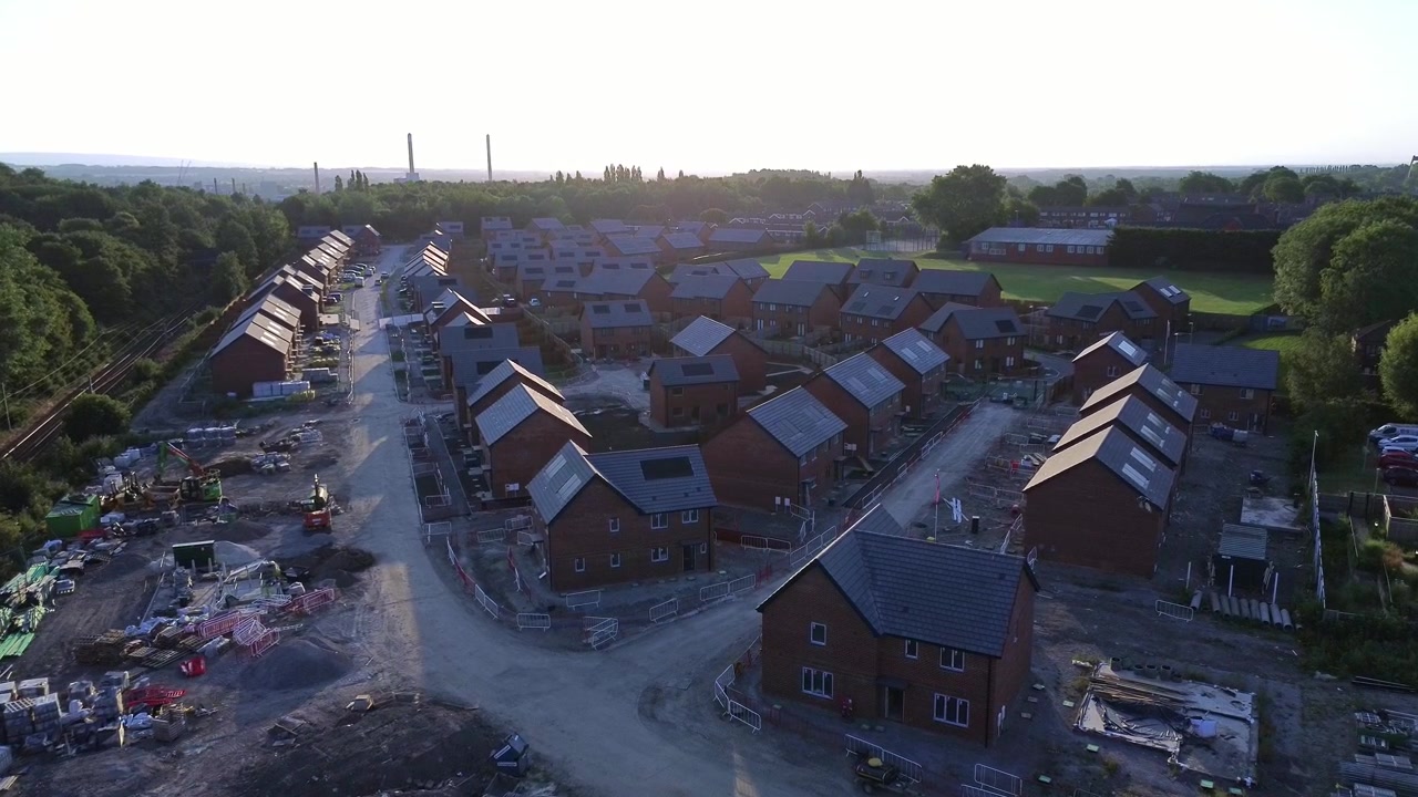 Affordable new home estate construction site aerial view above unfinished development at sunrise