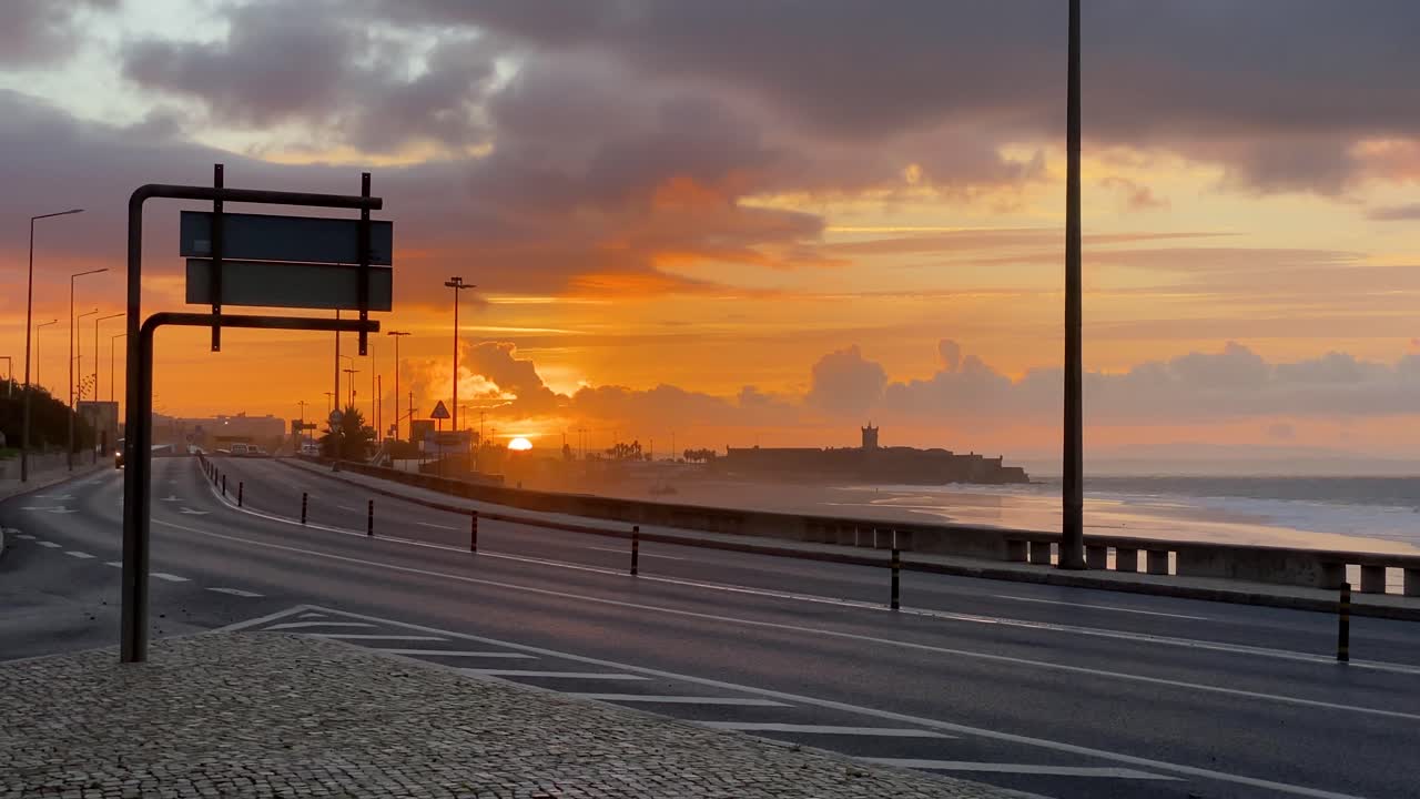 amplia vista de algunos autos moviéndose hacia un hermoso amanecer cerca de la playa en carcavelos, portugal