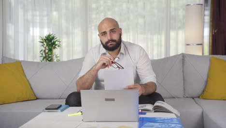 Home-office-worker-man-smiling-at-camera-looking-at-paperwork.