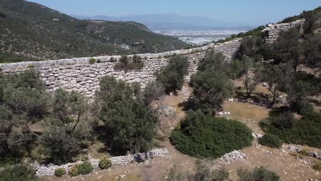 Drone-panning-from-the-left-to-the-right-side-of-the-frame,-moving-along-a-wall-in-Lycian-Way's-Hiking-Trail-located-in-Fethiye,-Turkey