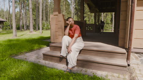 relaxed woman sitting on stairs outside home and enjoying the sun when her son appears from behind, covering her eyes and then hugging her