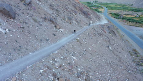 Two-motocross-bikers-driving-towards-each-other-on-steep-and-tiny-gravel-road