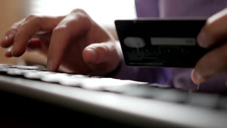 paying with a credit-card online, shopping. male hands with credit card during shopping through internet. computer keyboard. closeup. businessman made an electronic  payment.