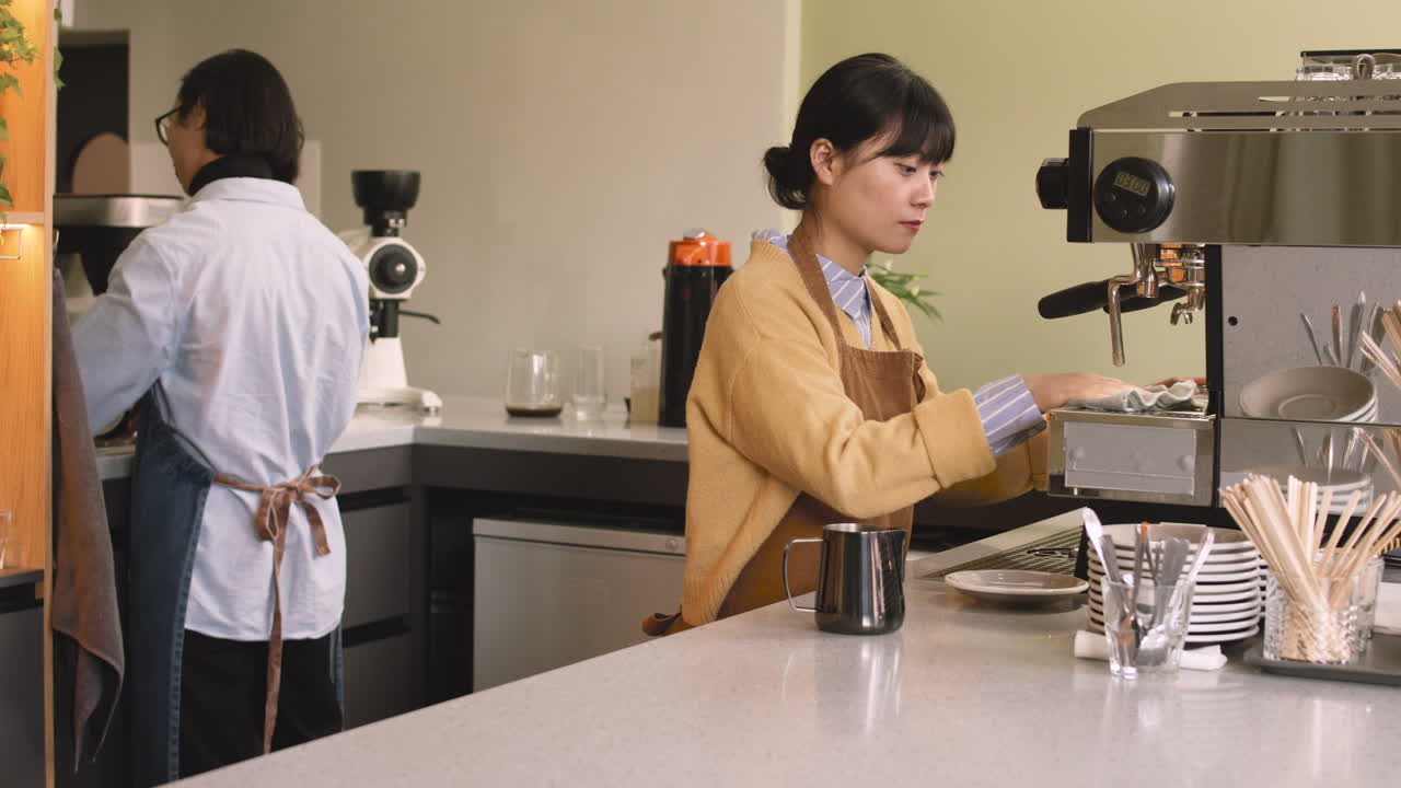 두 명의 웨이터가 커피숍에서 청소를 한 다음 휴식을 취하고 카메라를 보고 미소를 짓습니다.