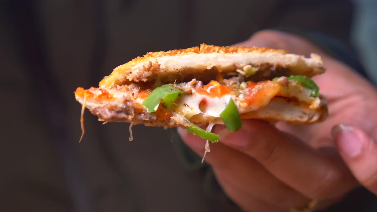 피자 샌드위치 한 조각을 들고 있는 손