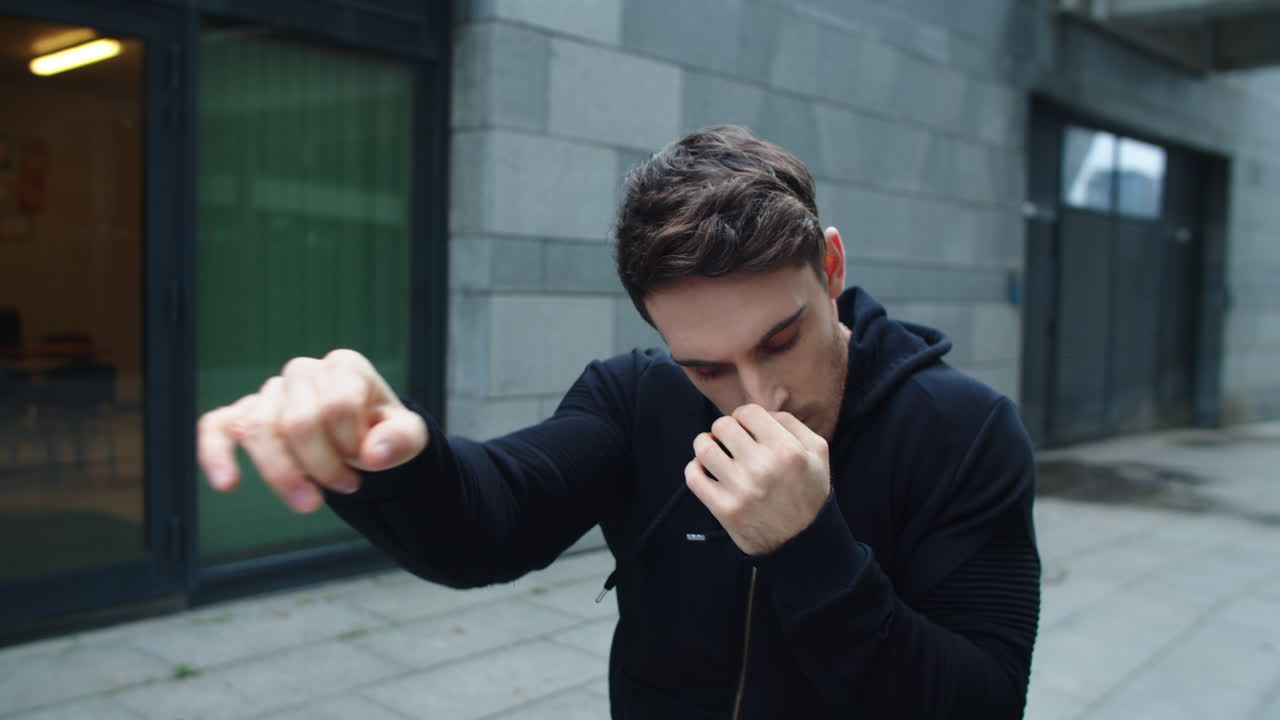 시내 거리에서 복싱  ⁇ 치를 훈련하는 집중된 남자. 야외에서 복싱하는 젊은 남자