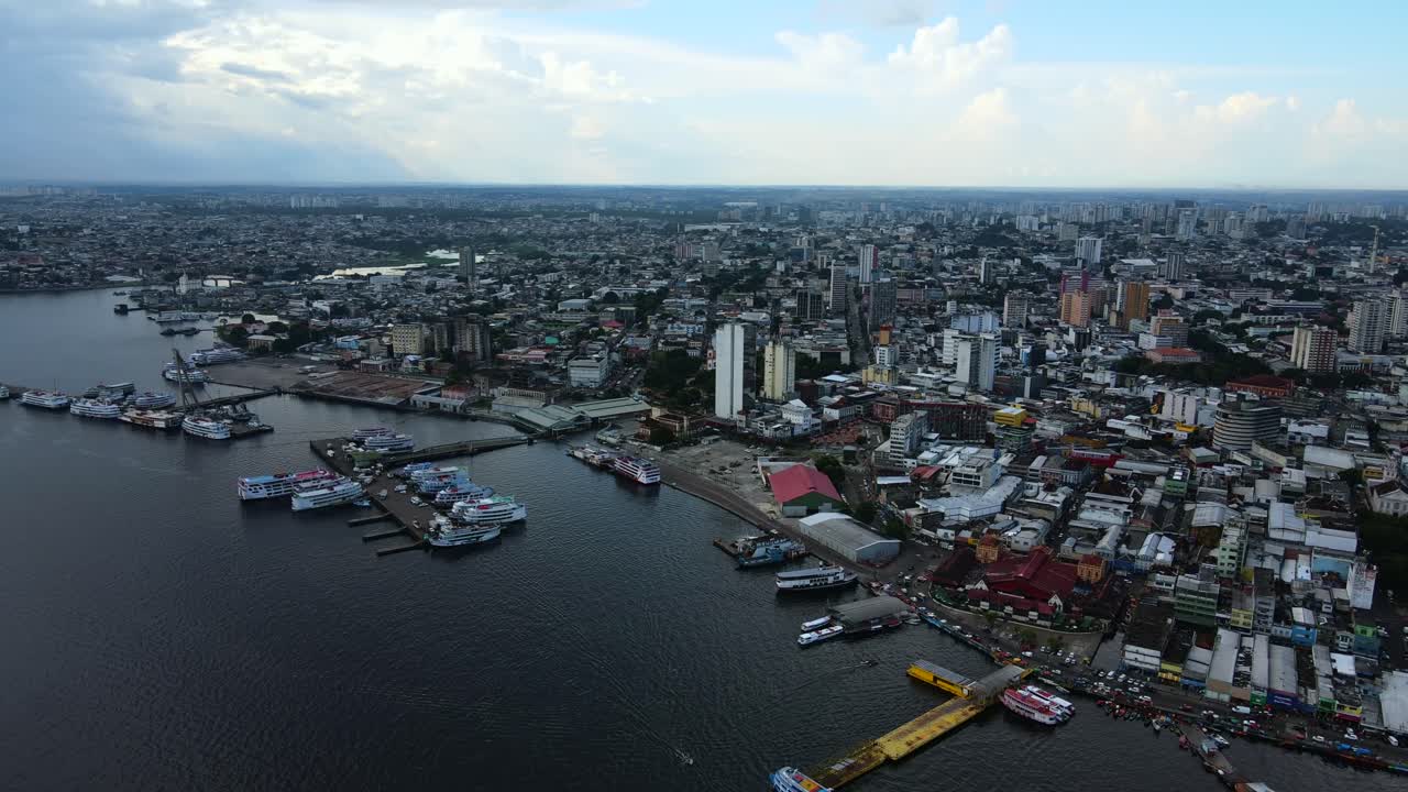 Il porto di Manaus e il Rio Negro durante un pomeriggio nuvoloso con una tempesta in avvicinamento in lontananza. Veduta aerea dall'alto che attraversa l'acqua e l'estensione della città in 4K.