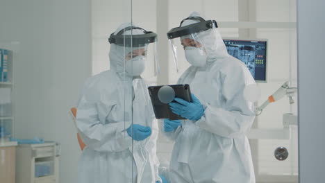 orthodontists wearing protection suits looking at tablet