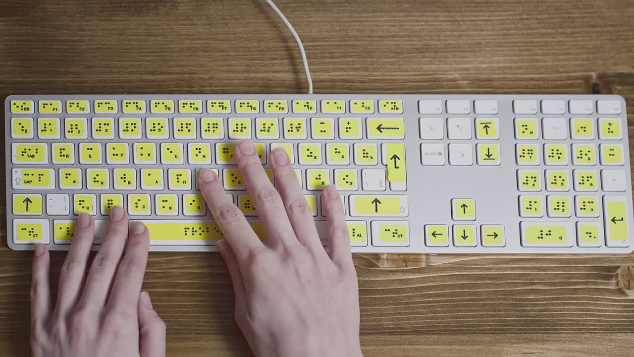 primer plano de un teclado de computadora con braille. una niña ciega está escribiendo palabras en los botones con sus manos. dispositivo tecnológico para personas con discapacidad visual.