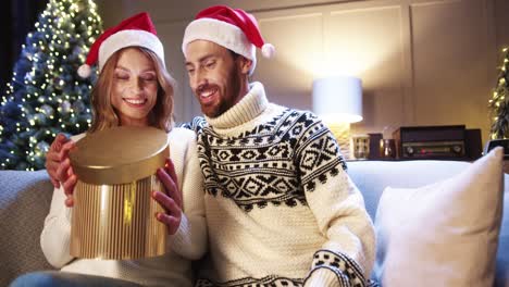 Primer-Plano-Retrato-De-Una-Esposa-Alegre-Que-Recibe-Y-Abre-Una-Caja-De-Regalo-De-Navidad-Del-Esposo-En-Casa