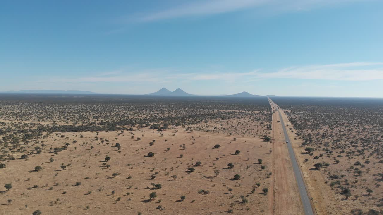 drones de alta altitud imágenes de video aéreo del interminable desierto de namibia, áfrica. drones volando hacia adelante y hacia atrás sobre la arena y los árboles del desierto con cielos azules y montañas en el horizonte.