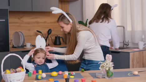 in the cozy room filled with art and plants, a woman is playfully placing bunny ears on a little girls head at the event table as they share a moment of joy