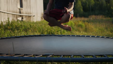 primer plano de un niño saltando en cámara lenta en un trampolín mientras está en una posición de loto