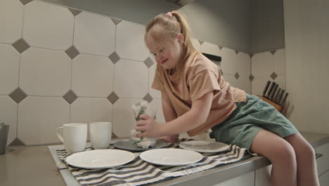 girl with down syndrome cleaning dishes in kitchen