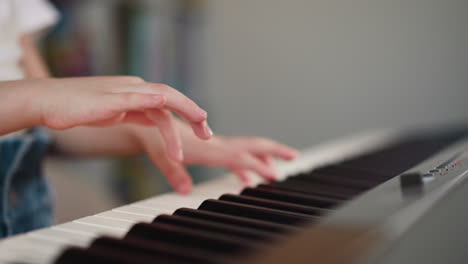 girl hands press keys on keyboard of musical instrument