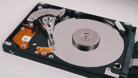 opened hard disk drive with spinning platter. move of writing magnetic head