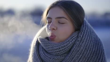 young woman keeping warm in a knitted scarf during winter