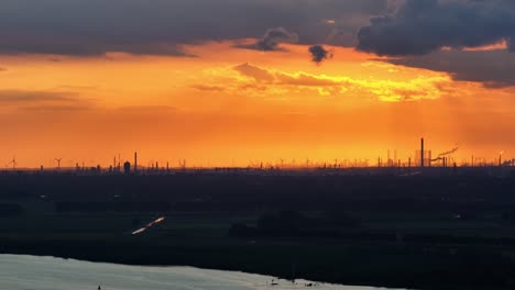 a very orange and dark sunset over barendrecht and the oude maas river