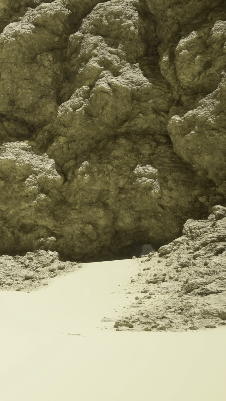 Rock formations and sandy area near a cave entrance during daylight