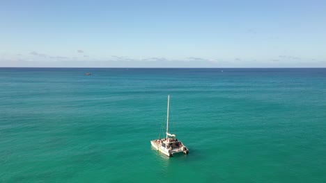 drone video of a catamaran sailing across turquoise ocean near waikiki beach, oahu, hawaii. a serene aerial moment capturing island leisure, nautical elegance, and the vast beauty of open water