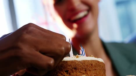 hand of businesswoman lighting candles on cake with colleague