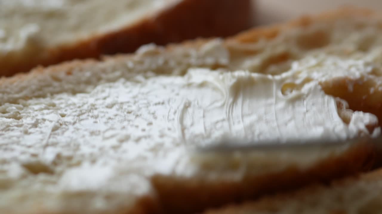 primer plano de la mantequilla que se está extendiendo sobre una rebanada de pan
