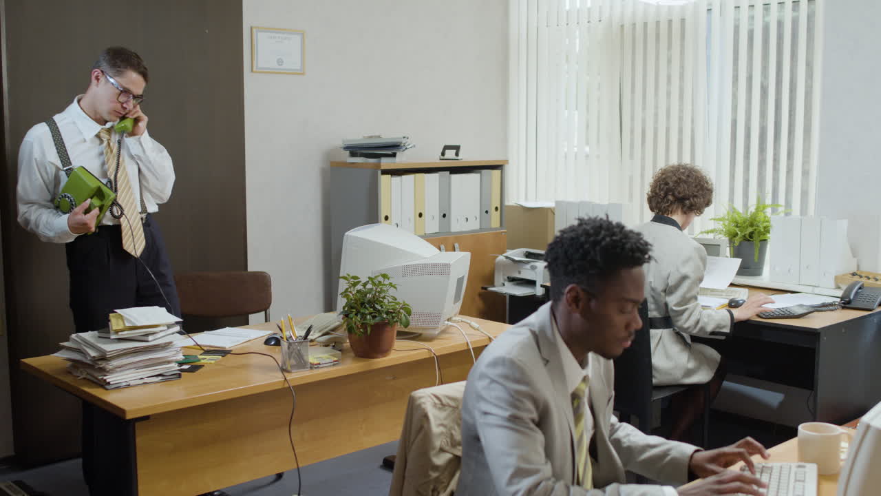 Caucasian businessman working stading near his desk and talking on the phone in a vintage office.