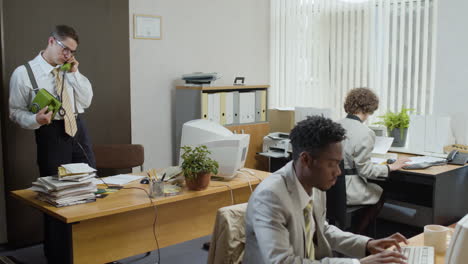 Caucasian-businessman-working-stading-near-his-desk-and-talking-on-the-phone-in-a-vintage-office.