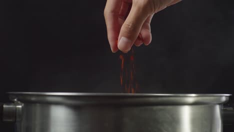 añadiendo escamas de pimienta roja a una olla
