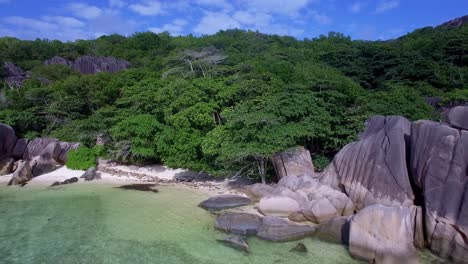 beach with granite rocks, white sand, and blue sky in tropical paradise, la digue, seychelles - drone shot