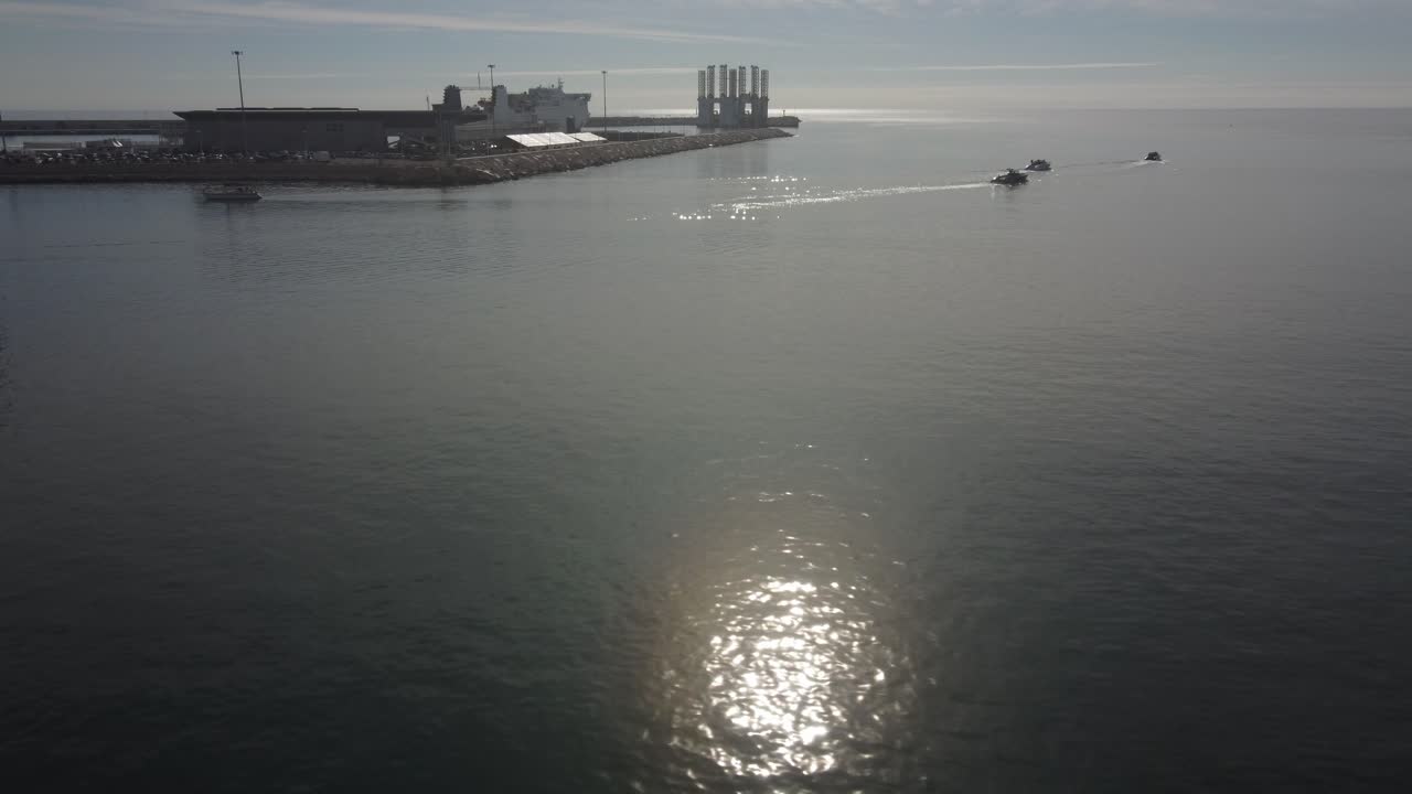 Flying towards the entrance of a busy small port. Haze in the air at sunrise.