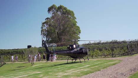 cámara lenta: pasajeros esperando para abordar un helicóptero negro privado en una bodega en la isla waiheke, nueva zelanda