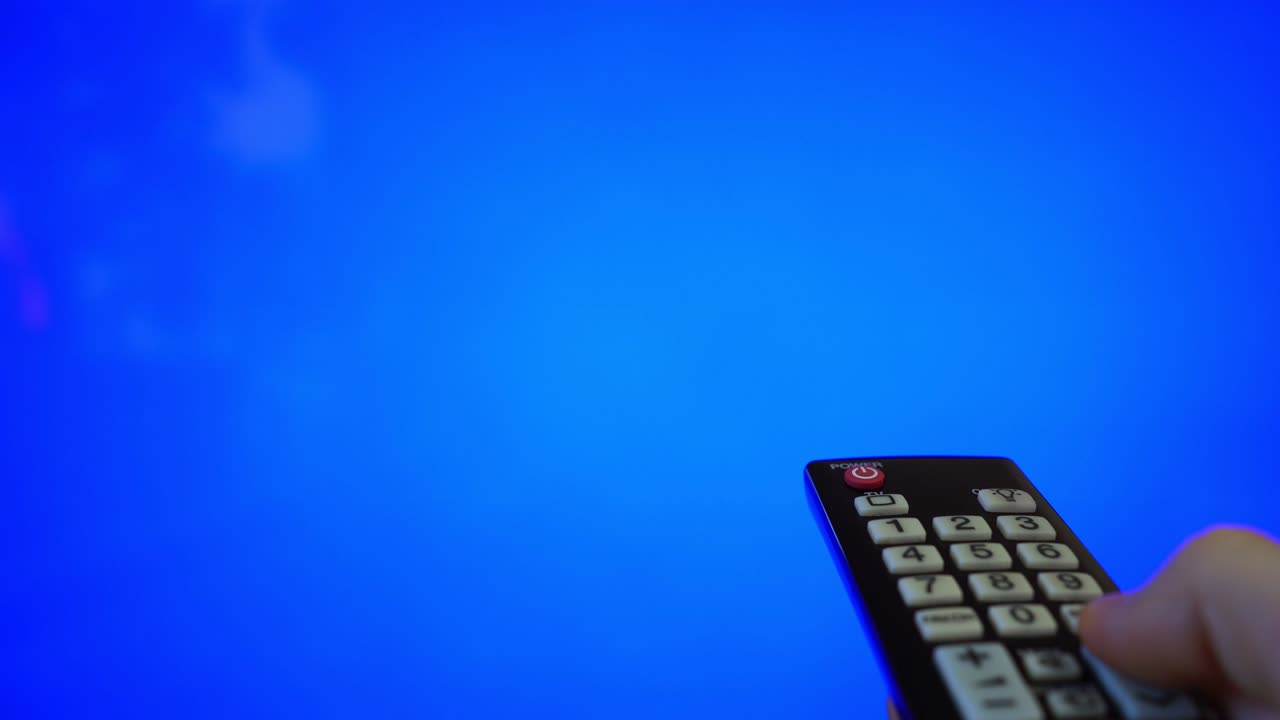 tv 화면을 가리키는 리모컨을 가진 남성 손. 파란색 크로마 키.