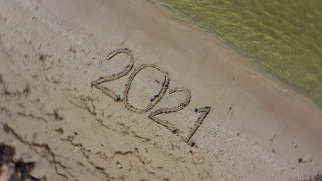 twenty twenty one written in the sand and spinning counterclockwise continuously making it a crazy year