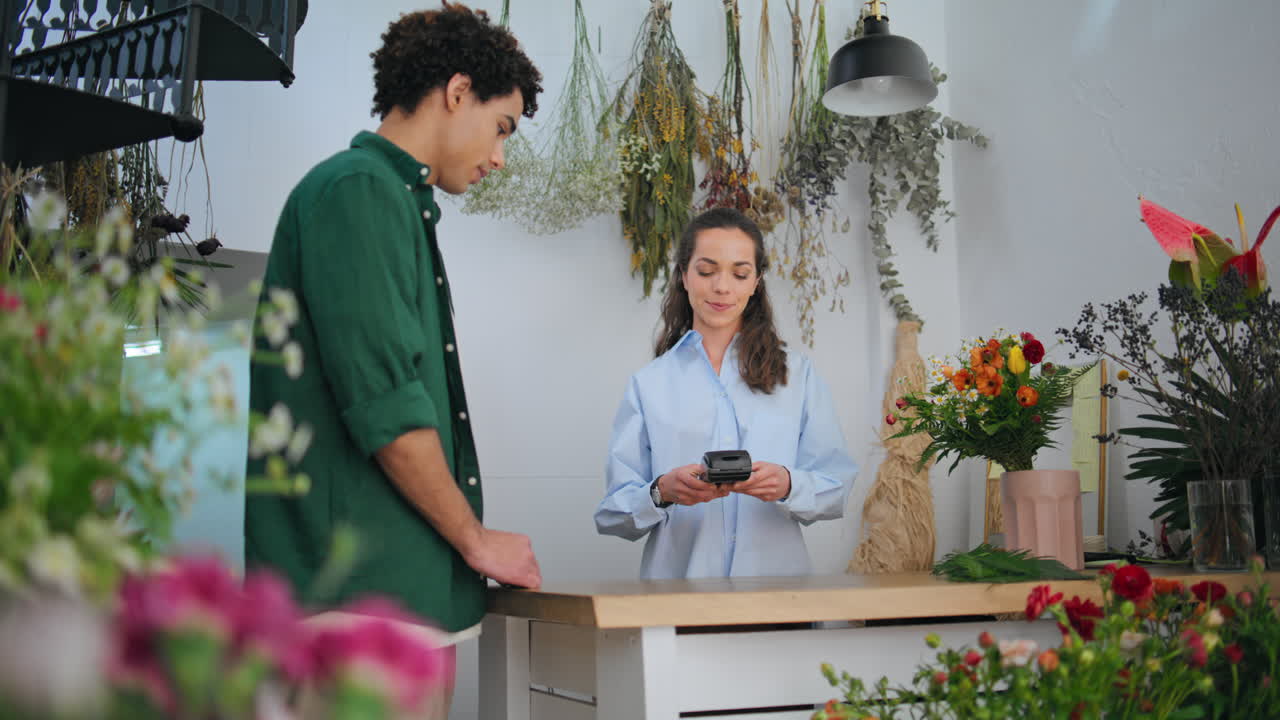 신용카드를 사용한 구매자는 현대적인 꽃 가게에서 꽃을 구입합니다.
