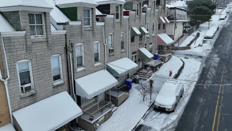 drone in discesa scatto di fila di case con portico durante il giorno invernale innevato