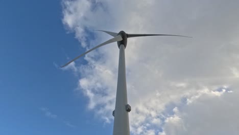 low angle time lapse of wind turbine looking up to blue sky and clouds