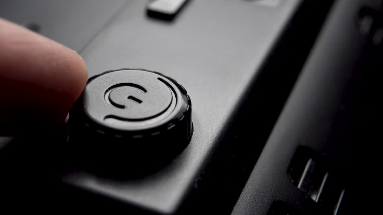 regolazione della potenza di un dispositivo elettrico nero. un dito gira il pulsante di alimentazione in plastica