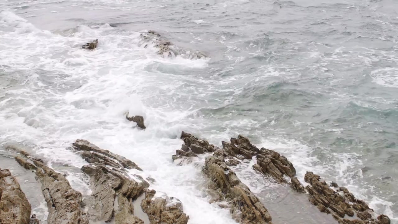 Onde del Pacifico che si infrangono lungo una costa frastagliata con cieli nuvolosi e paesaggio oceanico naturale