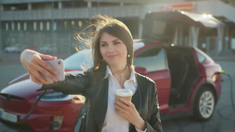 mujer tomando una selfie junto al coche eléctrico