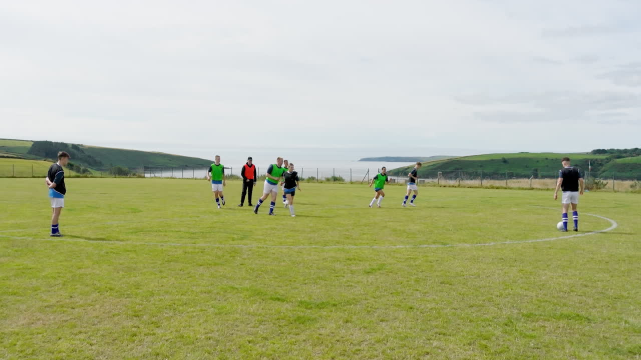 Male and female soccer players beginning game and passing ball, coach observing on pitch, copy space