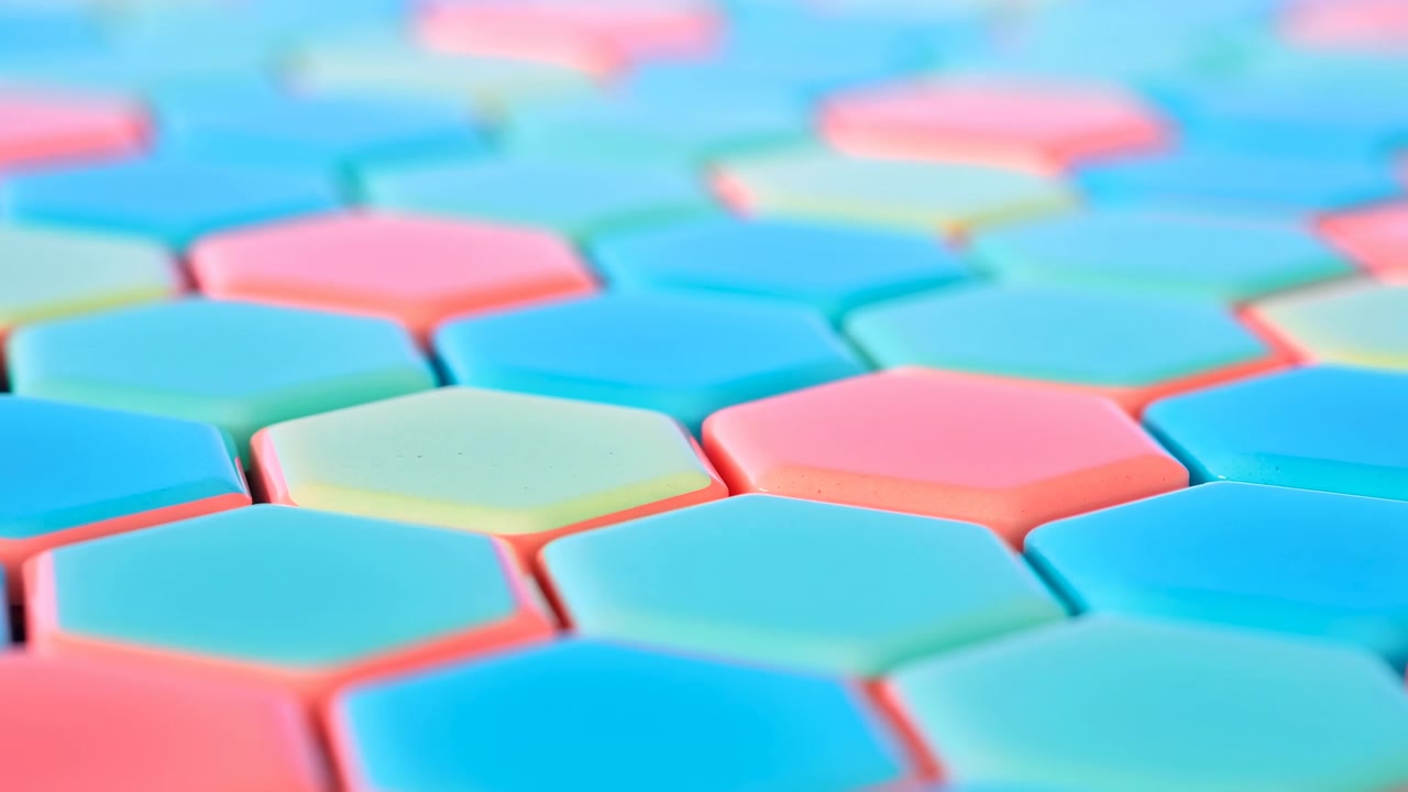 Macro primo piano di piastrelle esagonali pastello disposte in un motivo a nido d'ape ripetuto che riempie l'inquadratura. Piastrelle di plastica lisce opache in blu, rosa e verde menta
