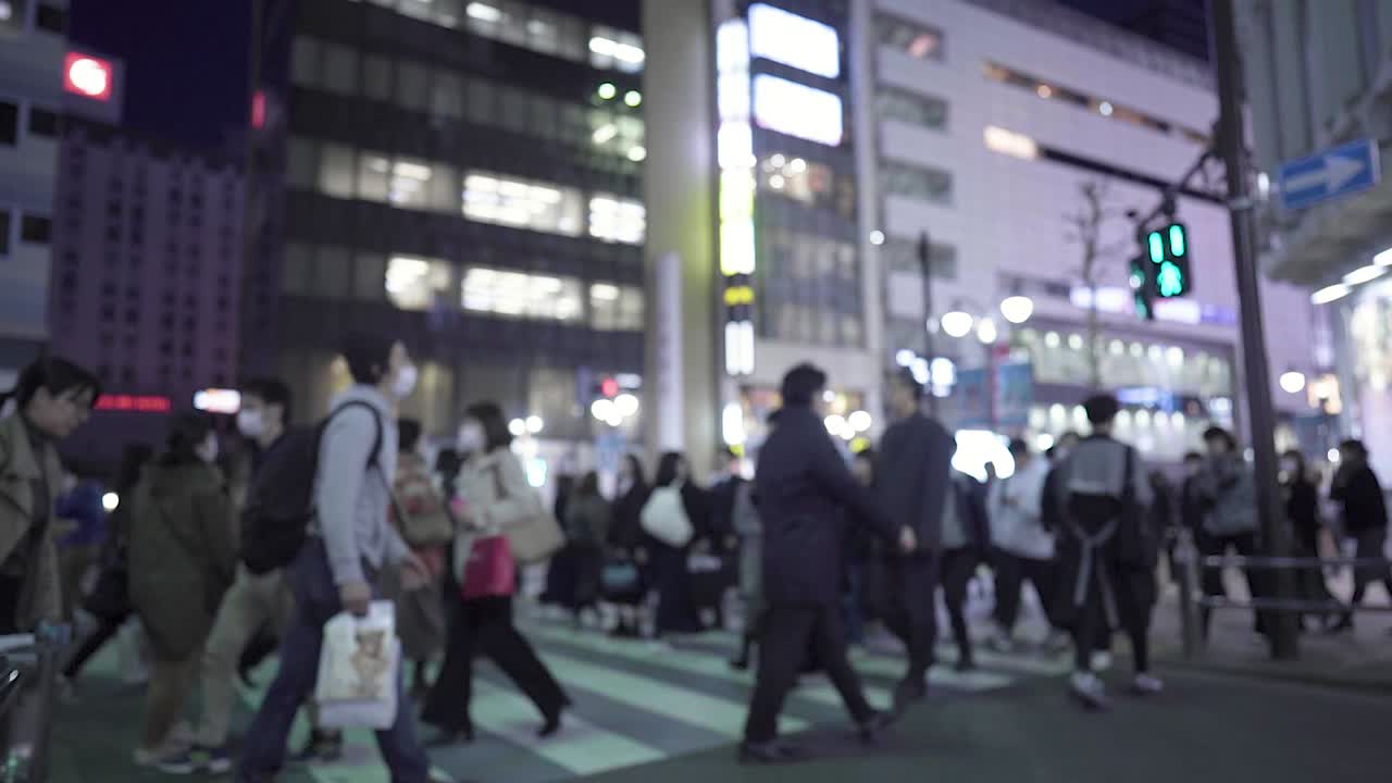Blurred view of people crossing a busy city street at night