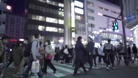 blurred view of people crossing a busy city street at night