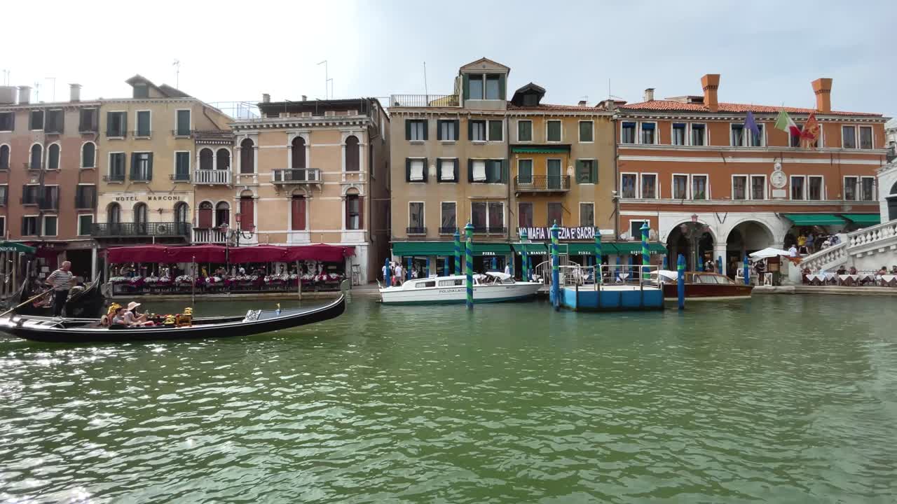 Exterior of Venetian Buildings By Rialto Bridge, Tourists Sightseeing On Gondola Towards the End.