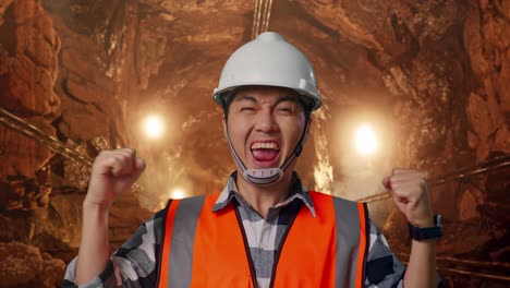 close up of asian male engineer with safety helmet screaming goal celebrating working in underground mine tunnel